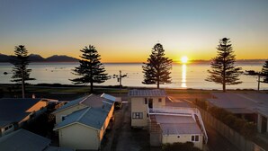 A residential area with houses and a view of the sunset over a body of water. - Waterfront | Handy Location | Affordable | Unit 6 - KK61646 (Kaikoura)