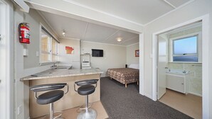 A compact kitchen with a bar area, a bed, and a bathroom with a window. - Waterfront | Handy Location | Affordable | Unit 6 - KK61646 (Kaikoura)