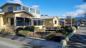 A motel with a two-story building, a picnic table, and a signboard. - Waterfront | Handy Location | Affordable | Unit 7 - KK41647 (Kaikoura)