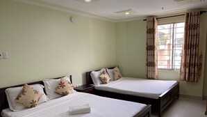 A hotel room with two single beds, each with a wooden frame and white bedding. There is a window with curtains, and the walls are painted a light green color. - Hoang Tay 1 Hotel by Bay Luxury (Ho Chi Minh City)