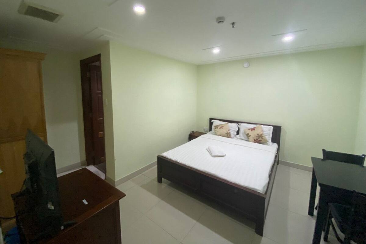 A bedroom with a bed, bedside table, and a desk with a chair.