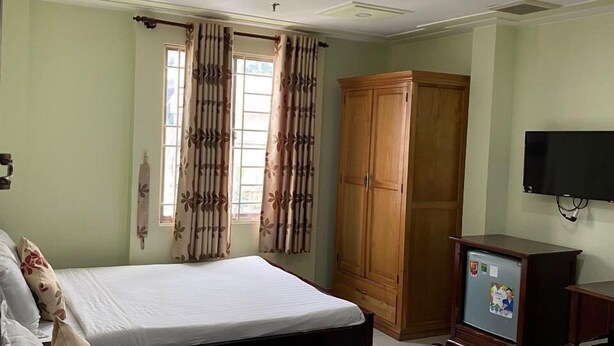 A hotel room with two beds, a wardrobe, a television, and a window with curtains. - Hoang Tay 1 Hotel by Bay Luxury (Ho Chi Minh City)