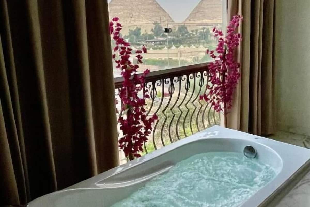 A bathtub with a view of the pyramids through a window.