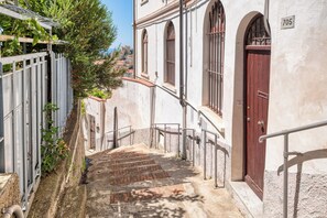 A narrow stairway leading to a building with a red door and the number 705.