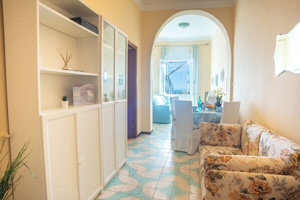 A hallway with a sofa, a cabinet, and a window with curtains.