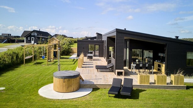 Une maison moderne dotée d’un patio, d’un jacuzzi et d’un espace de jeux.