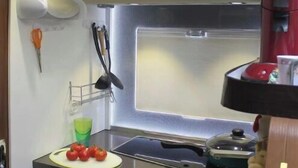 Una cocina compacta con microondas, cafetera y lavabo.