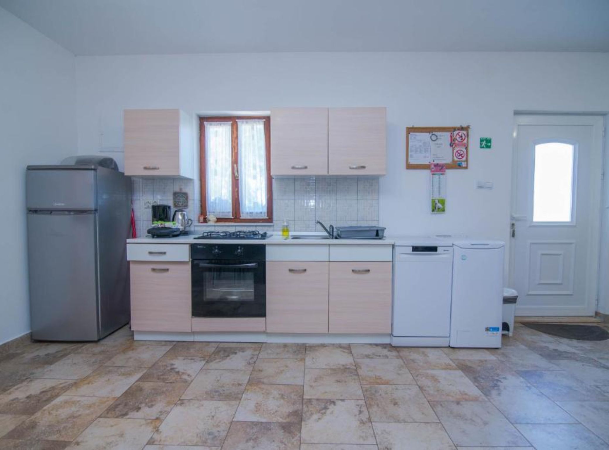Een keuken met een koelkast, fornuis, oven en vaatwasser.