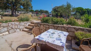 An outdoor seating area with stone steps, wicker chairs, and a table with a tablecloth. - Veli Lošinj Hilltop Oasis (Mali Losinj)