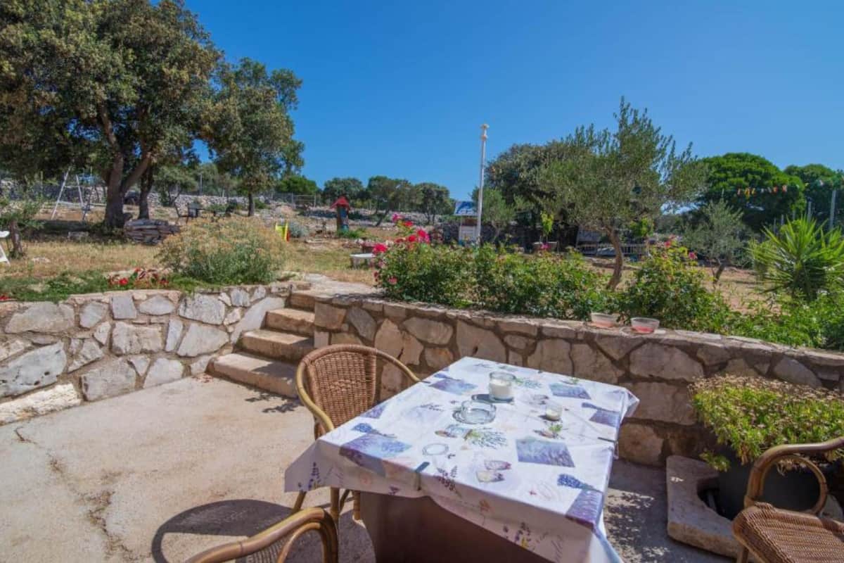 An outdoor seating area with stone steps, wicker chairs, and a table with a tablecloth.