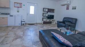 A compact living space with a kitchenette, a sofa, a television, and a ceiling fan. - Veli Lošinj Hilltop Oasis (Mali Losinj)