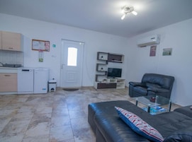 Un espacio habitable pequeño con kitchenette, un sofá, un televisor y un ventilador de techo.