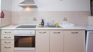 A kitchen with a dishwasher, oven, sink, and a stainless steel range hood. - Veli Lošinj Hilltop Oasis (Mali Losinj)