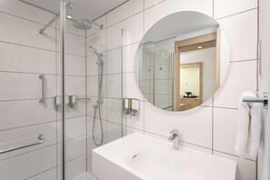 A modern bathroom with a glass-enclosed shower, a white sink, and a large mirror. - Hampton By Hilton Nuneaton (Nuneaton)