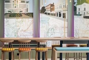 Un bar con taburetes de madera y un banco, con vistas a una calle a través de grandes ventanales.