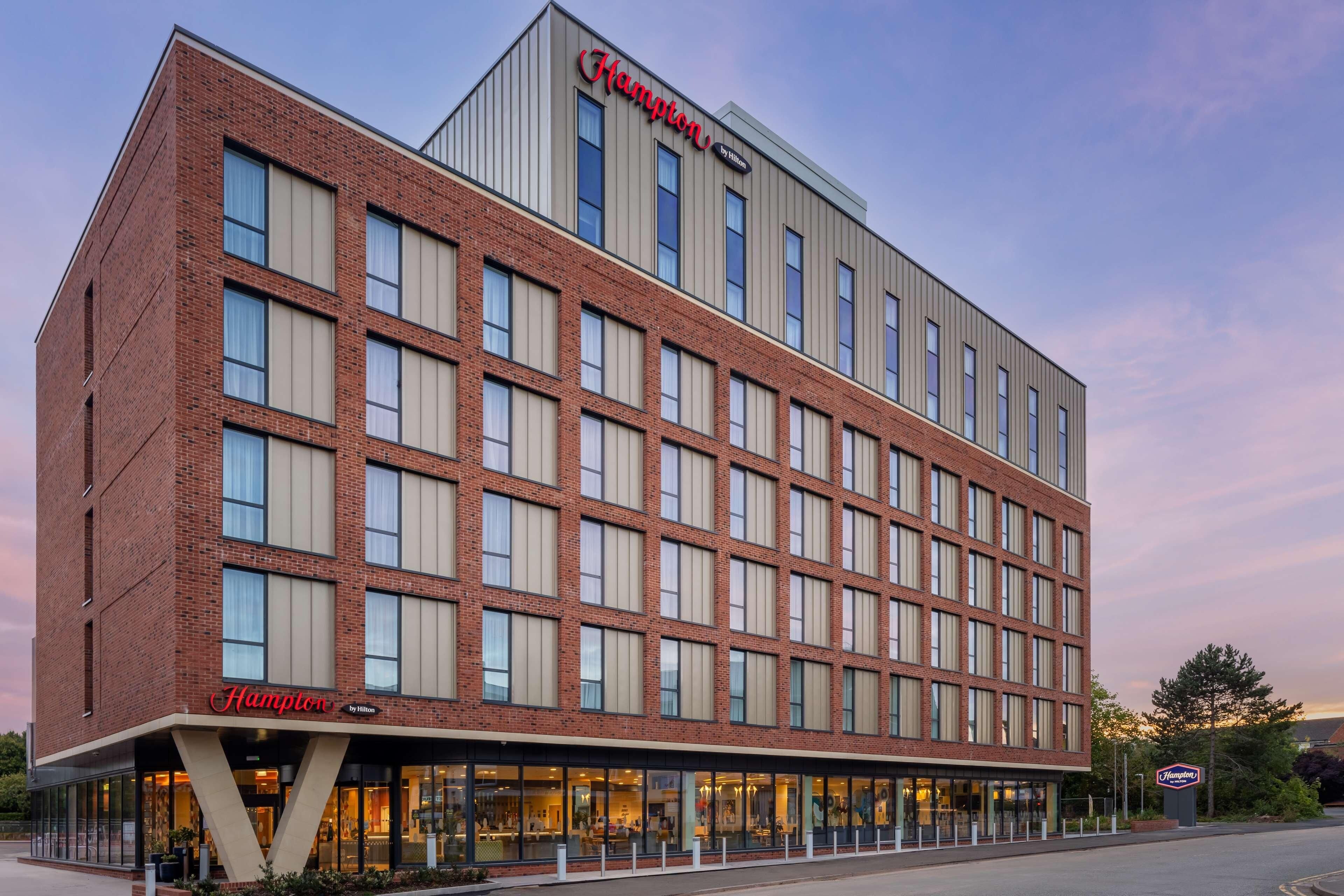 Un hotel Hampton by Hilton con fachada de ladrillo, ventanas amplias y techo plano.