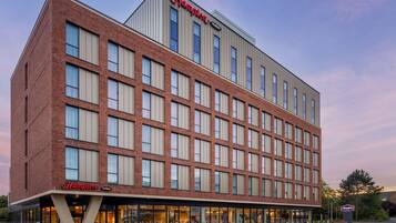 A Hampton by Hilton hotel with a brick facade, large windows, and a flat roof.