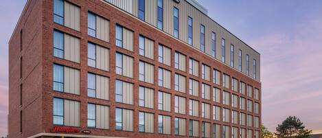 Un hotel Hampton by Hilton con fachada de ladrillo, ventanas amplias y techo plano.
