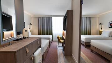 A hotel room with two beds, a desk, a TV, and a small seating area.