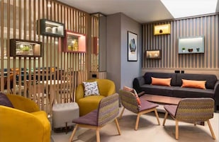 Una sala de estar moderna con un sofá, sillones, una mesa de centro y un separador decorativo.