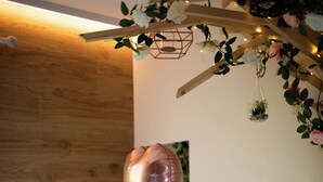 A spa room with a wooden wall, a massage table, a small table with a candle, and a heart-shaped balloon. - Luxury suite with private Spa and Sauna (Bligny-sur-Ouche)