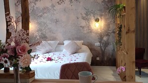 A bedroom with a bed, a wooden table with a mug, a vase with flowers, and a wall with a tree mural. - Luxury suite with private Spa and Sauna (Bligny-sur-Ouche)