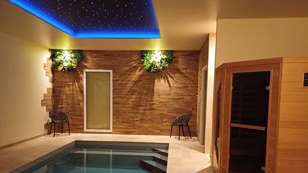 A swimming pool with a wooden wall and a starry ceiling. There are two chairs and a wooden cabinet. - Luxury suite with private Spa and Sauna (Bligny-sur-Ouche)