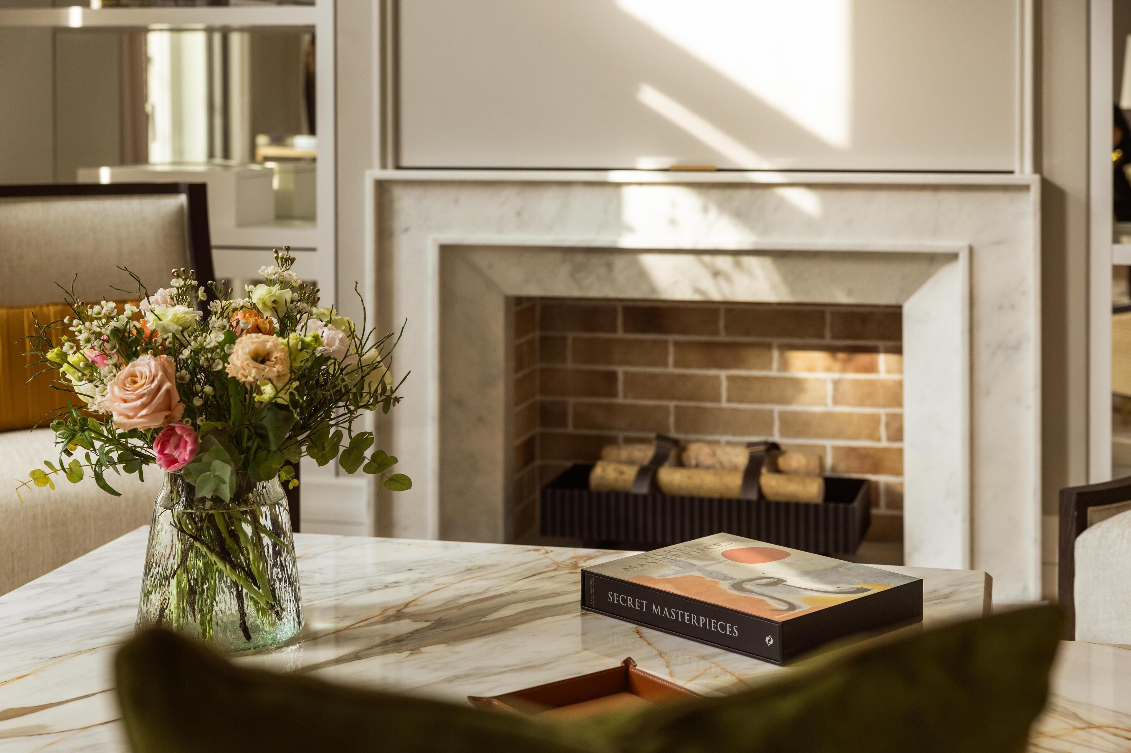Une table en marbre ornée d’un vase de fleurs et d’un livre intitulé « CHEF-D’ŒUVRES SECRETS ».