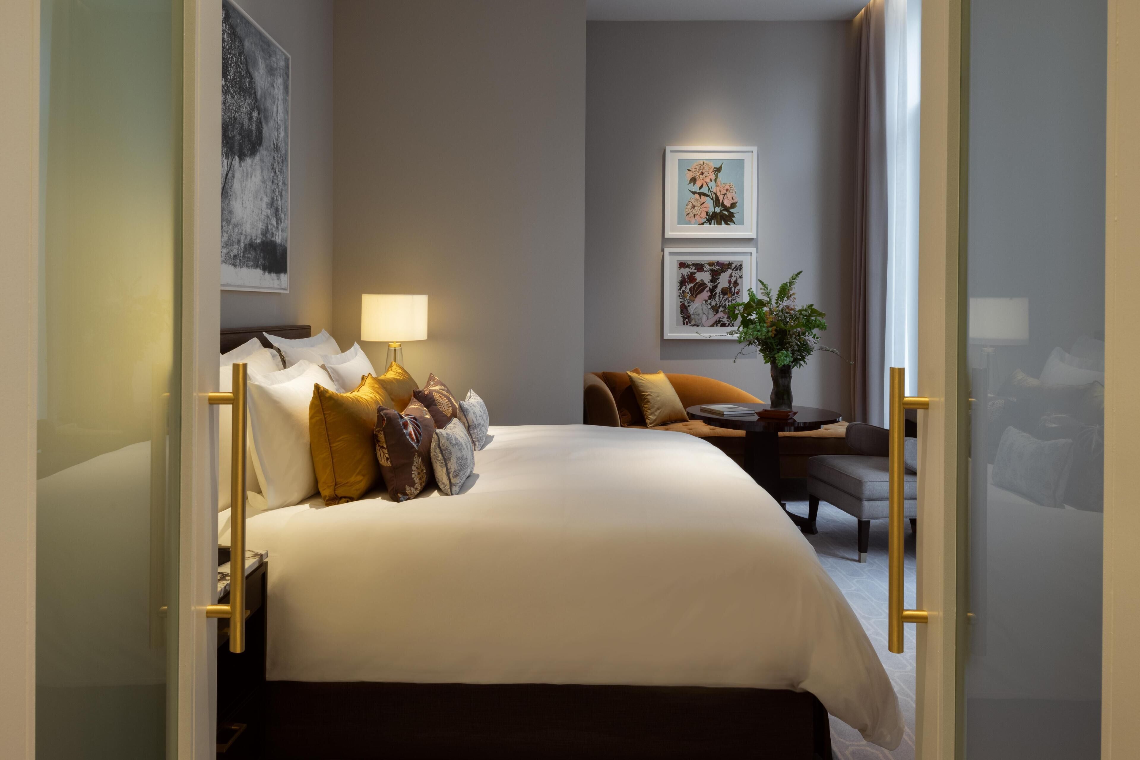 Habitación de hotel con una cama grande, un sofá, una mesita y una planta en maceta.