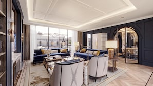 Un salon spacieux, doté d’un grand canapé, d’une table basse et offrant une vue sur la ville grâce à de grandes fenêtres.