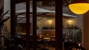 Un espace extérieur aménagé avec des tables, des chaises, des parasols et des plantes en pot.