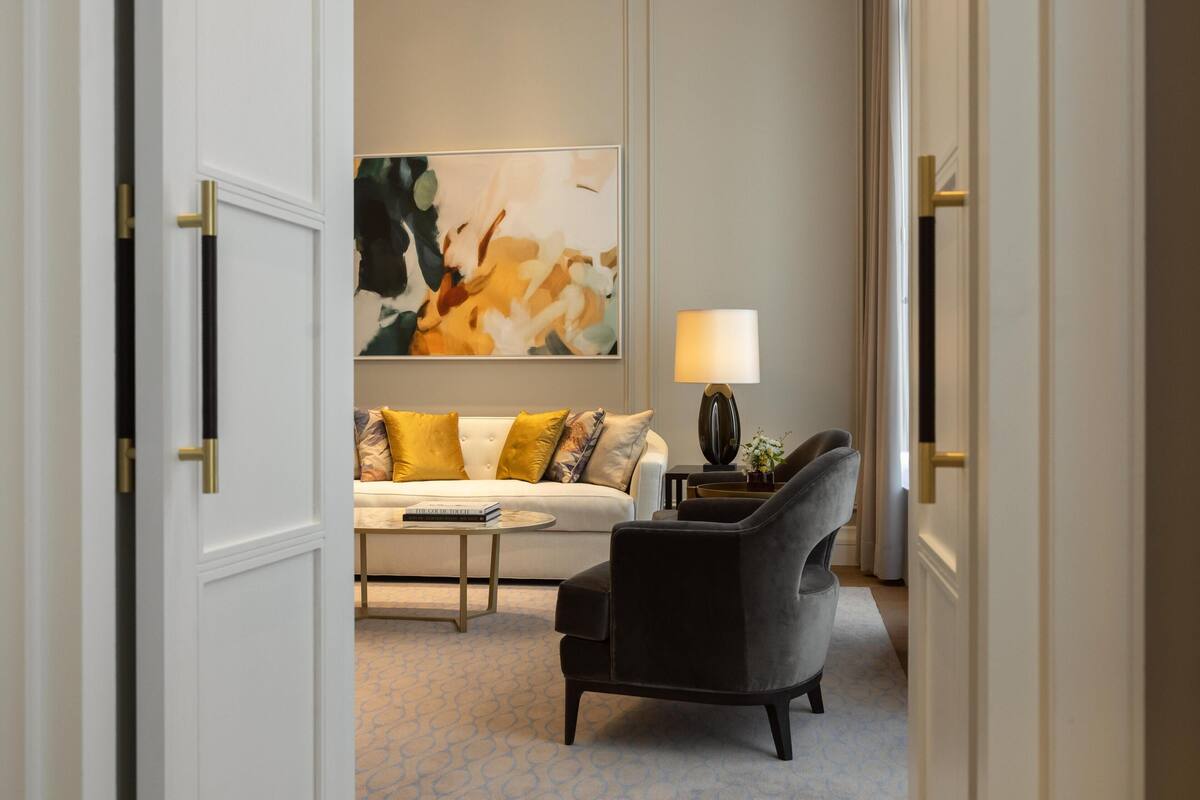 Ett modernt hotellrum med en vit soffa, en svart fåtölj, ett soffbord och en tavla på väggen.