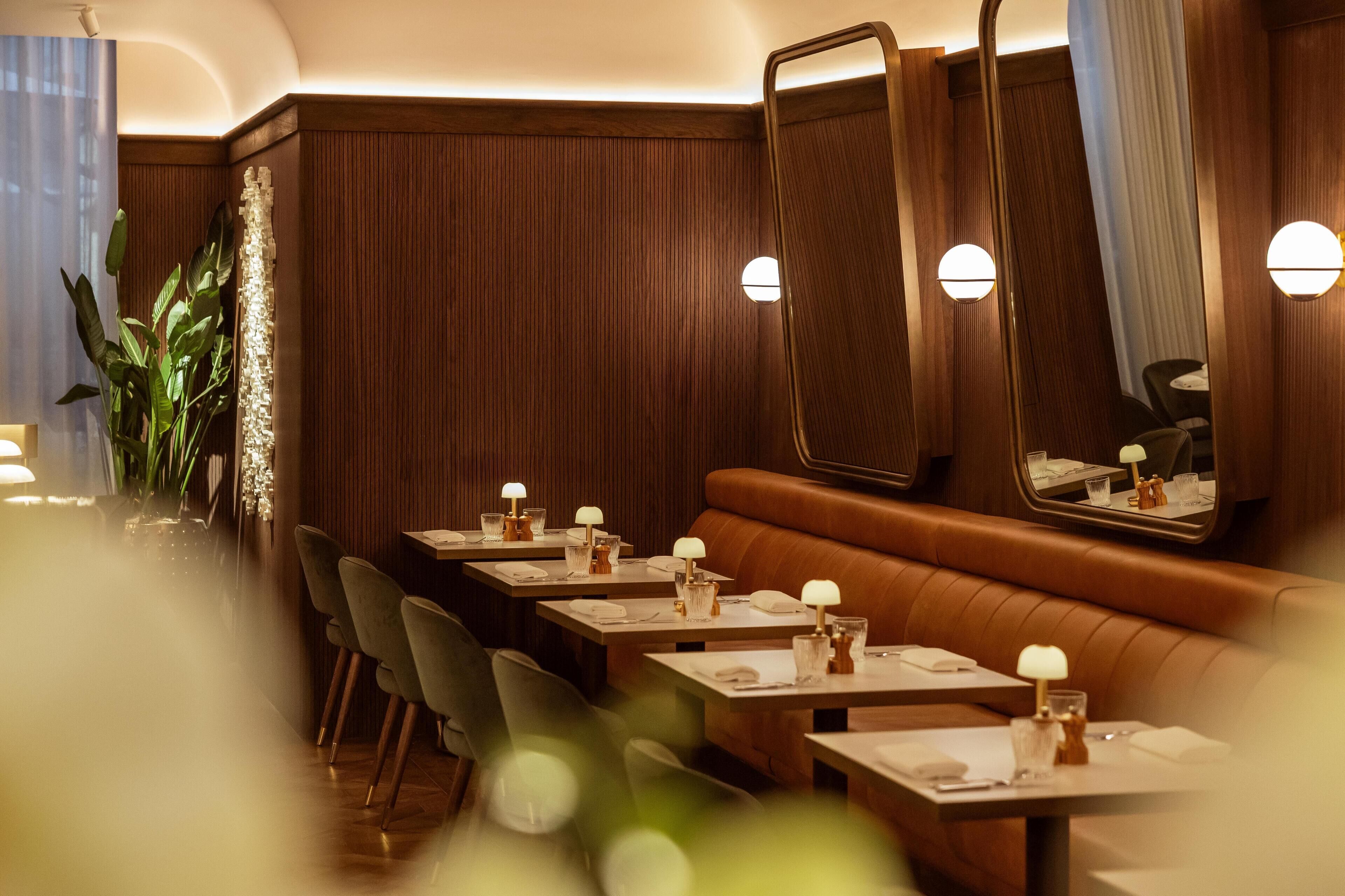 A restaurant with wooden paneling, a mirror, and tables set with glasses and napkins.