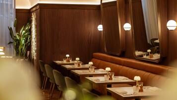 A restaurant with wooden paneling, a mirror, and tables set with glasses and napkins.