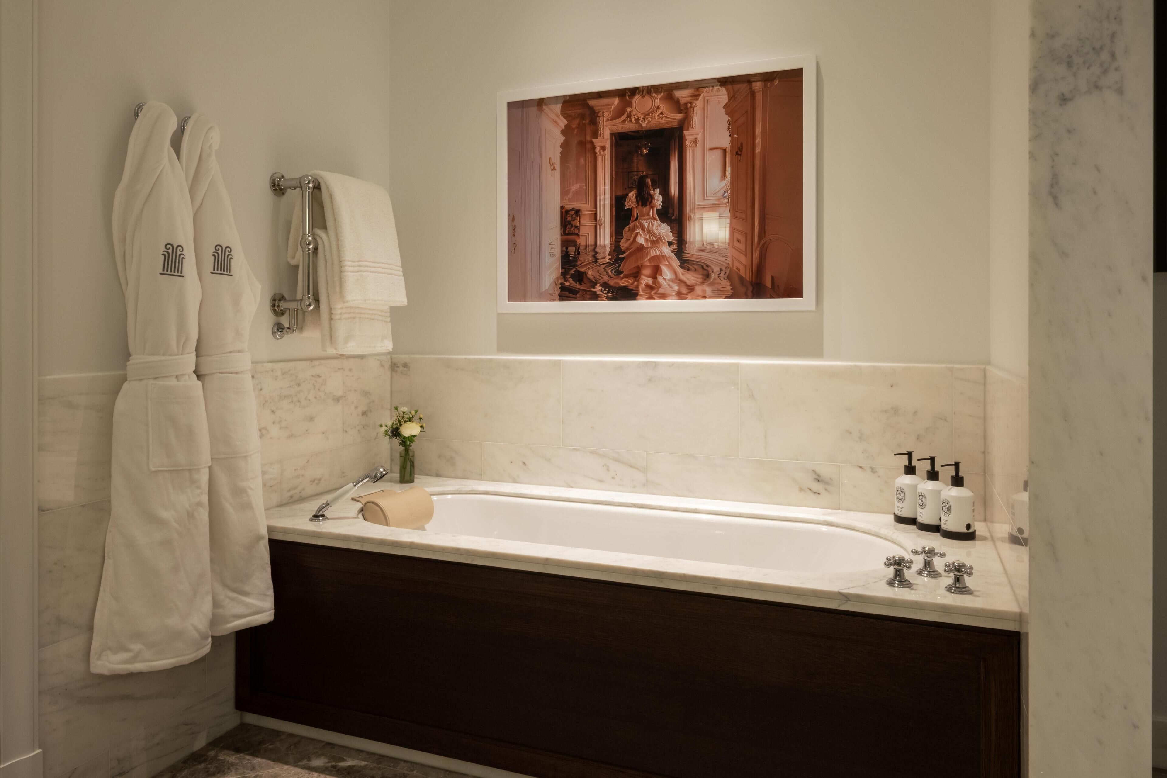 Une salle de bain moderne avec un lavabo en marbre, une baignoire et un tableau encadré au-dessus du miroir.