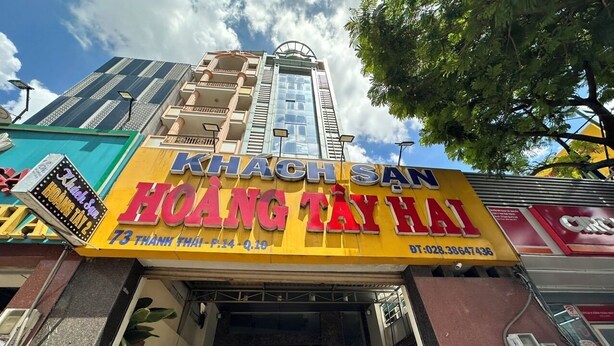 A building with a sign for 'KHACH SAAN HOANG TAY HAI' and a contact number. - Hoang Tay 2 Hotel by Bay Luxury (Ho Chi Minh City)