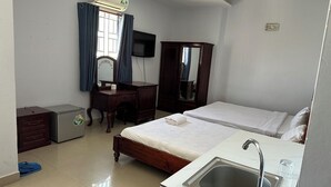 A hotel room with two beds, a desk, a small refrigerator, a sink, and a television. - Hoang Tay 2 Hotel by Bay Luxury (Ho Chi Minh City)