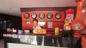 A hotel reception desk with a clock, a 'Lê Tân Reception' sign, and Visa payment terminals. - Hoang Tay 2 Hotel by Bay Luxury (Ho Chi Minh City)