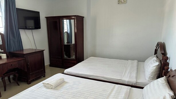 Una habitación de hotel con dos camas, un escritorio, un armario y una televisión.