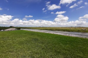 Un campo cubierto de césped con un canal de agua y un puente de madera.