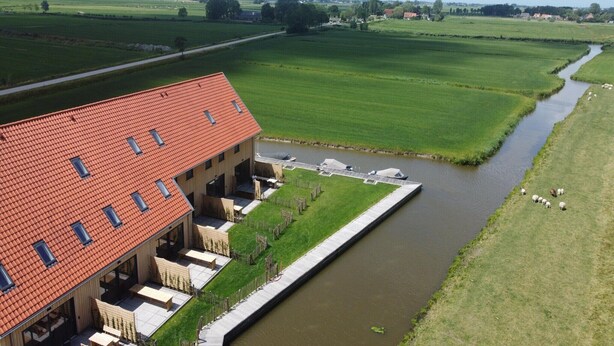 A building with a red roof, a canal, and green fields. - Villa in Leons near Frisian Lake District (Leons)