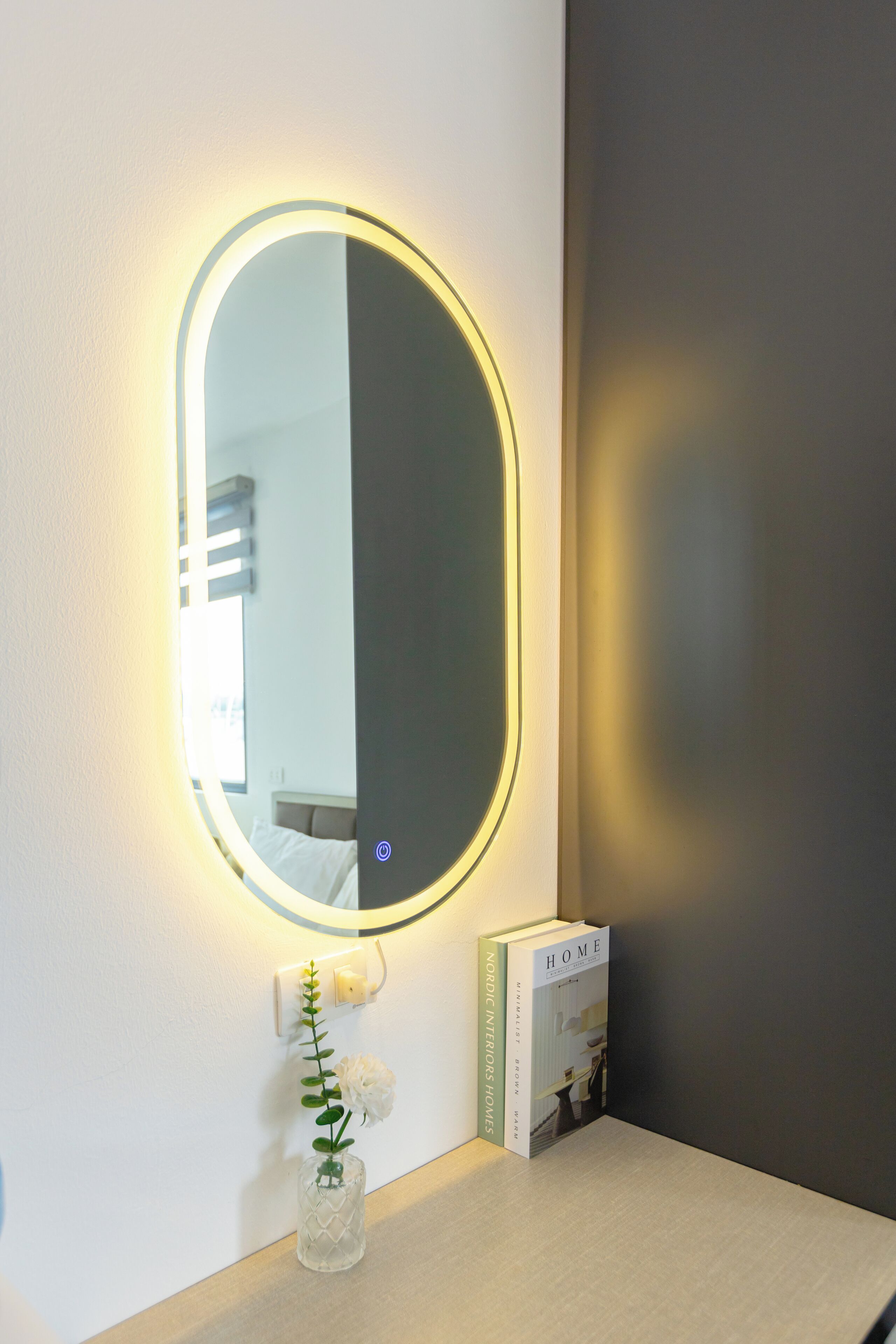 A bathroom with a round mirror, a small vase with a flower, and a book titled "Nordic Interiors".