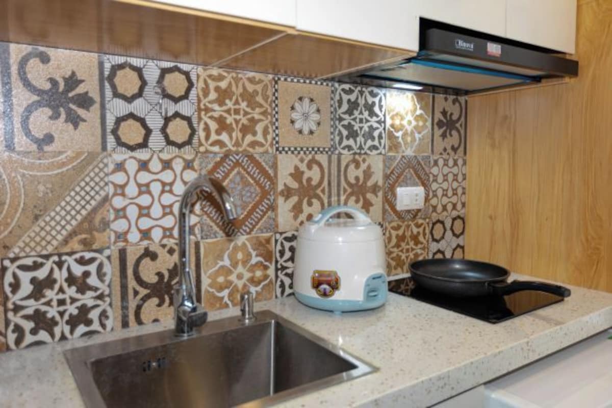 A kitchen with a sink, a kettle, and a frying pan on the countertop.