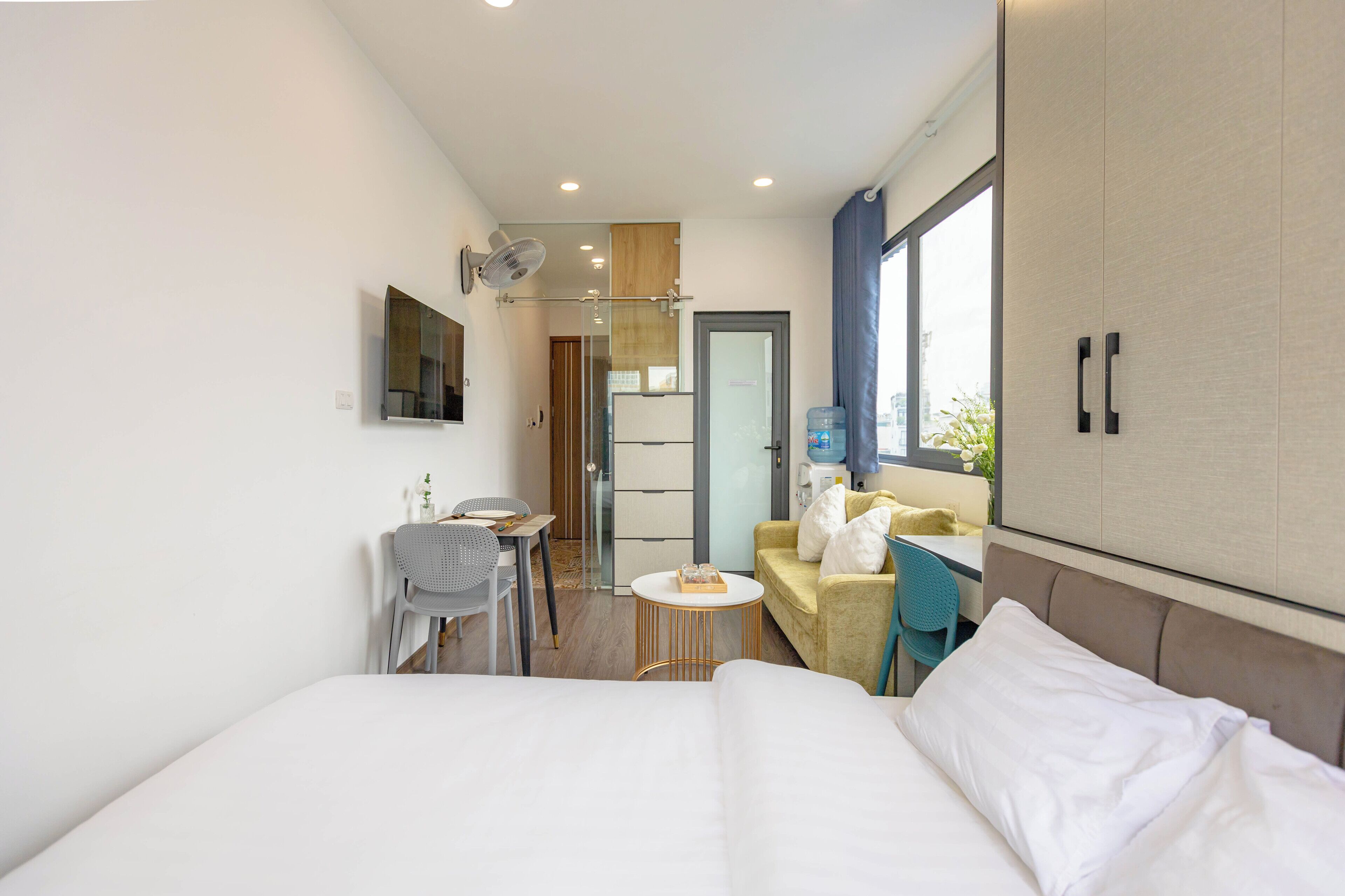 A hotel room with a bed, a small table, a sofa, a chair, and a wardrobe.