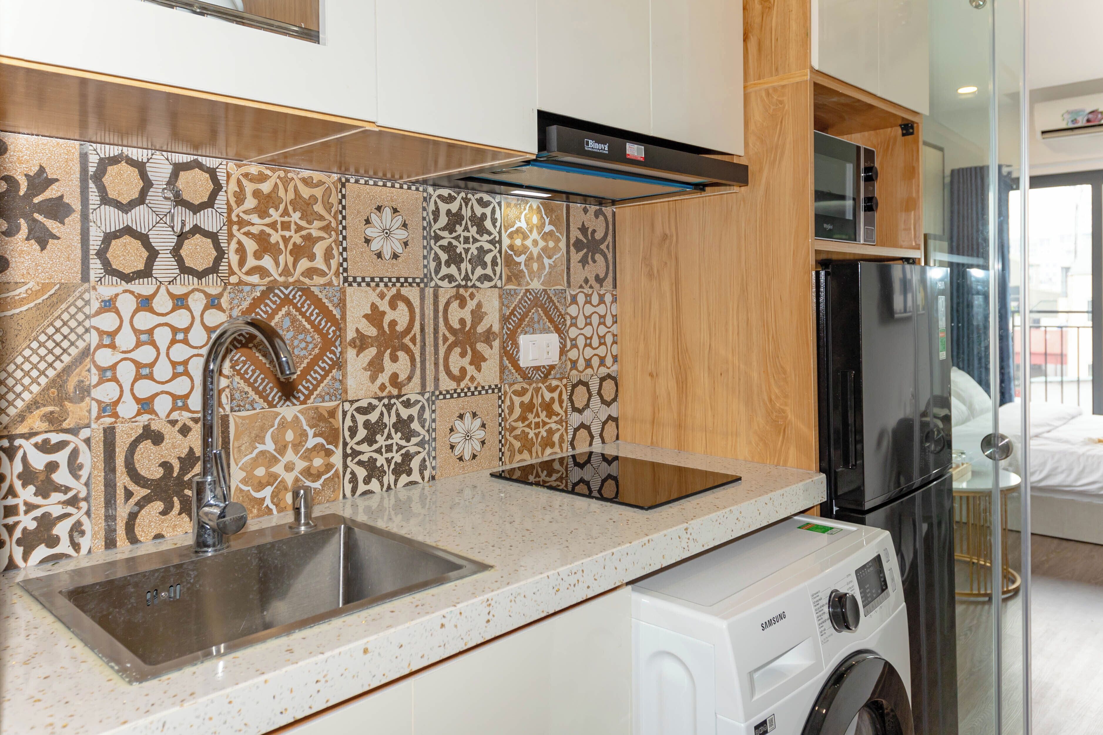 A kitchen with a stainless steel sink, a microwave, and a washing machine.