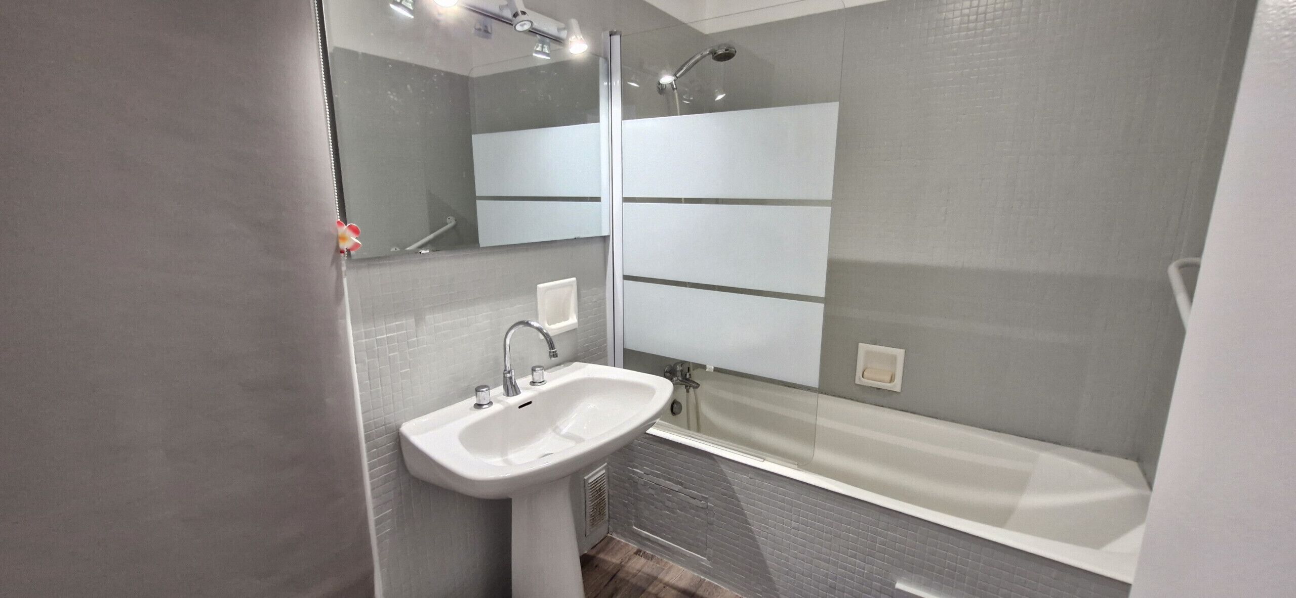 A modern bathroom with a white sink, a mirror, and a bathtub.