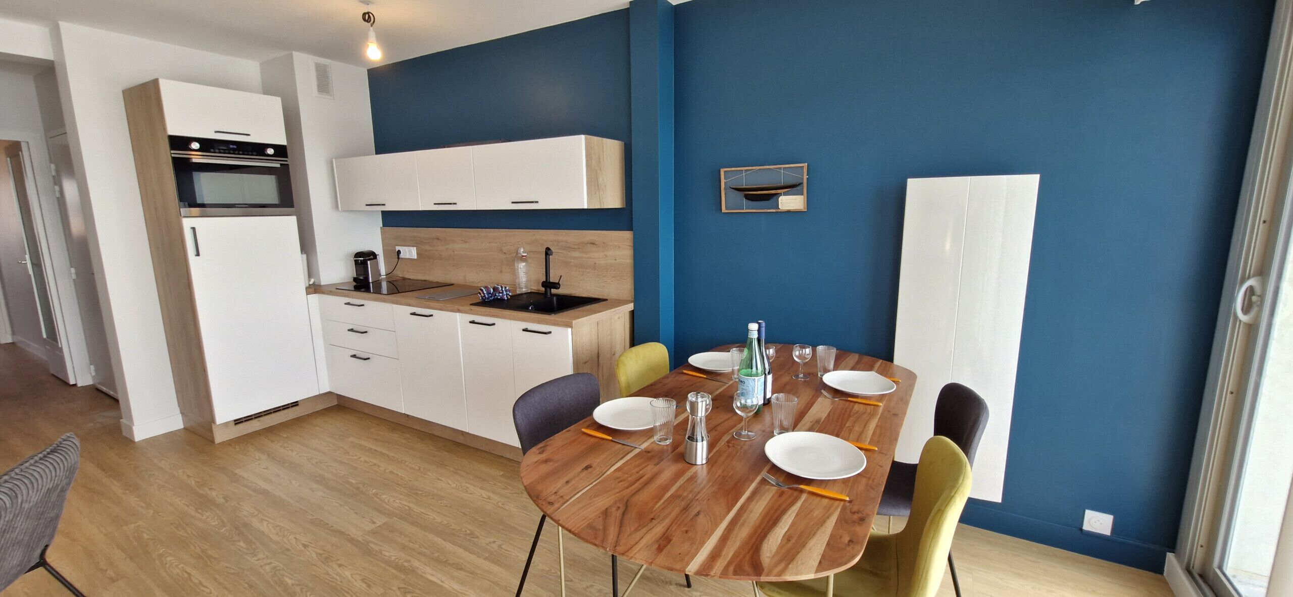 A modern kitchen with white cabinets, a built-in oven, and a wooden countertop.