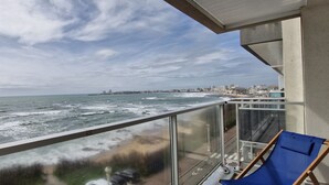 Un balcon avec vue sur l’océan et sur le paysage urbain.