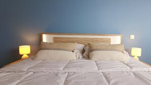 Una cama doble con cabecera de madera, dos lámparas de noche y almohadas color beige.