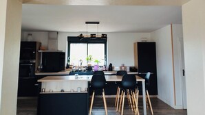 Et moderne køkken med en central ø, sorte stole og et vindue med planter.